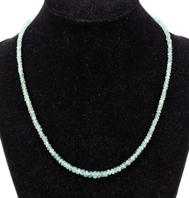 Le collier est composé de perles de verre et comporte une perle verte.