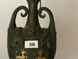un vase noir orné de motifs dorés sur fond blanc