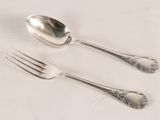 two spoons and a fork on a white table
