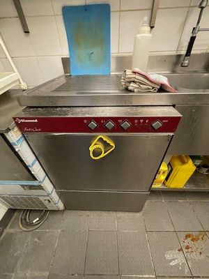 stainless steel dishwasher in a commercial kitchen with dirty flooring