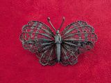 a butterfly brooch on a red surface