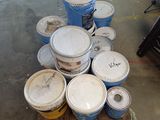 plusieurs seaux de peinture posés sur une palette dans un garage