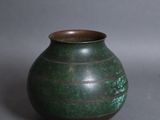 un petit vase vert posé sur une surface grise