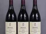 three bottles of red wine are lined up on a table