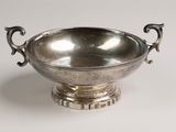 silver plated bowl with two handles on a pedestal on a white background