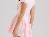 a woman in a pink gingham dress poses for a picture