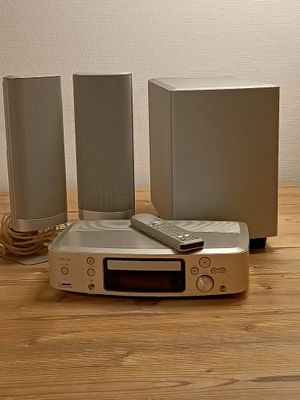 trois haut-parleurs et une télécommande posés sur une table en bois