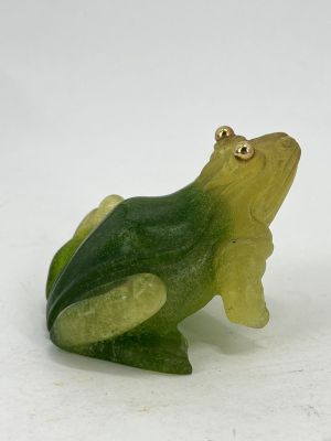 a green and yellow frog figurine sitting on a white surface