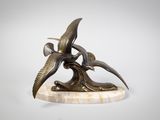 sculpture représentant deux oiseaux volant au-dessus d'une branche d'arbre, posée sur un socle en marbre