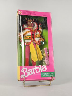 poupée Barbie dans une boîte rose posée sur une surface blanche avec un fond rose