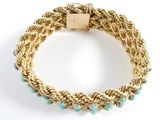a close up of a gold bracelet with turquoise beads on a white background