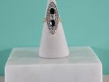 une image représentant une bague ornée d'une pierre noire posée sur un bloc de marbre blanc