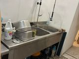 a sink in the corner of a kitchen with a lot of clutter on the floor