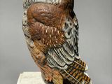 statue d'un hibou posé sur un socle blanc, sur fond gris