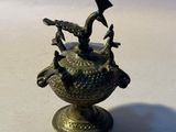 a small bronze vase with a bird on top of it
