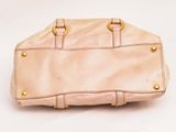 beige leather handbag on white background with gold hardware