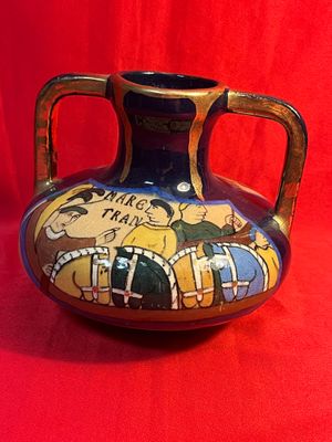 un vase orné d'une peinture, posé sur un tissu rouge