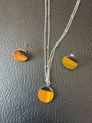 un gros plan d'un collier et de boucles d'oreilles posés sur une surface en cuir