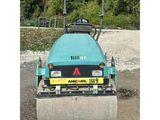 an image of a blue road roller sitting on top of a gravel road