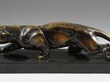 une photo d'une sculpture en bronze représentant un tigre sur un socle noir
