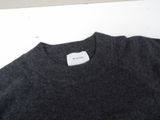 grey sweater with white label on it sitting on a white surface