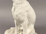 statue of a white dog with a collar sitting on a stone base