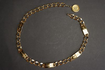a close up of a gold chain bracelet with a coin on it