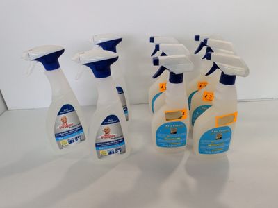 Plusieurs flacons de produits d'entretien sont alignés sur une surface blanche