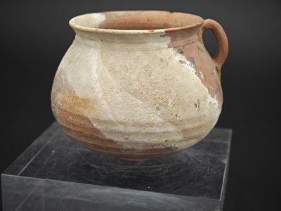 un vase marron et blanc posé sur une surface noire