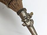 a close up of a broom with a metal handle on a white surface