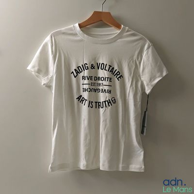 un t-shirt blanc avec un imprimé noir, accroché à un mur