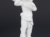 a white figurine of a boy with a flute on a pedestal