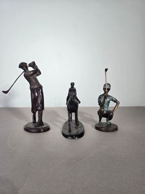 trois figurines représentant un homme et une femme jouant au golf