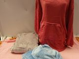 un lit recouvert d'une couverture rose et d'un sweat à capuche rouge posé dessus