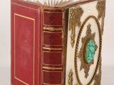 a red book with gold trim and a turquoise stone in the middle