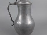 an antique silver coffee pot with a handle on a gray background
