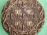 a metal plate with a design on it on a green surface