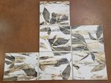 four coasters with gold and black leaves on them sitting on a table