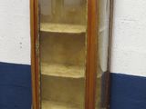 une petite armoire avec une porte vitrée, dans un coin