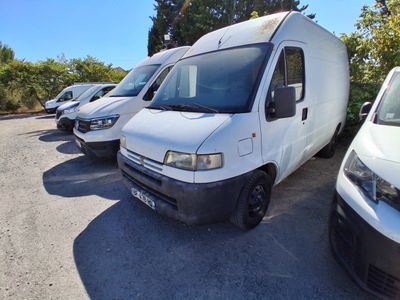 plusieurs fourgonnettes blanches garées sur un parking, avec des arbres en arrière-plan