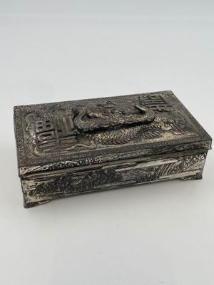 a silver box with a bird on it sitting on top of a table