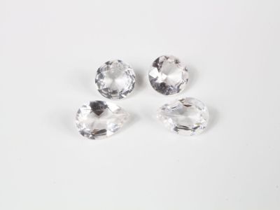 un ensemble de trois pierres de cristal transparent posées sur une surface blanche