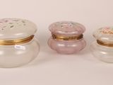 three small glass jars with lids are sitting on a white surface