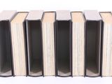several books are stacked on top of each other on a white surface