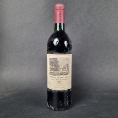a bottle of wine sitting on top of a table next to a gray background