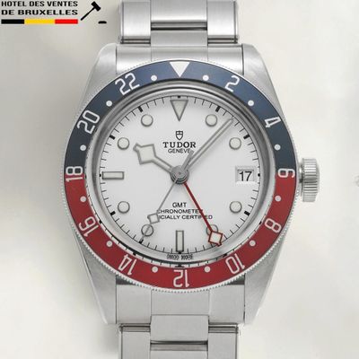 a silver watch with a red and blue bezel on it
