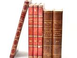 several old books are stacked on top of each other on a white surface