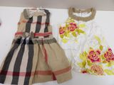 two dresses on a white table with a pink flower on it
