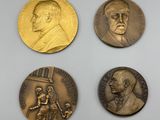 quatre médailles de bronze sur lesquelles figurent les portraits d'hommes et de femmes