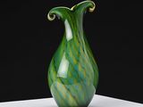 a green and white vase sitting on a white table